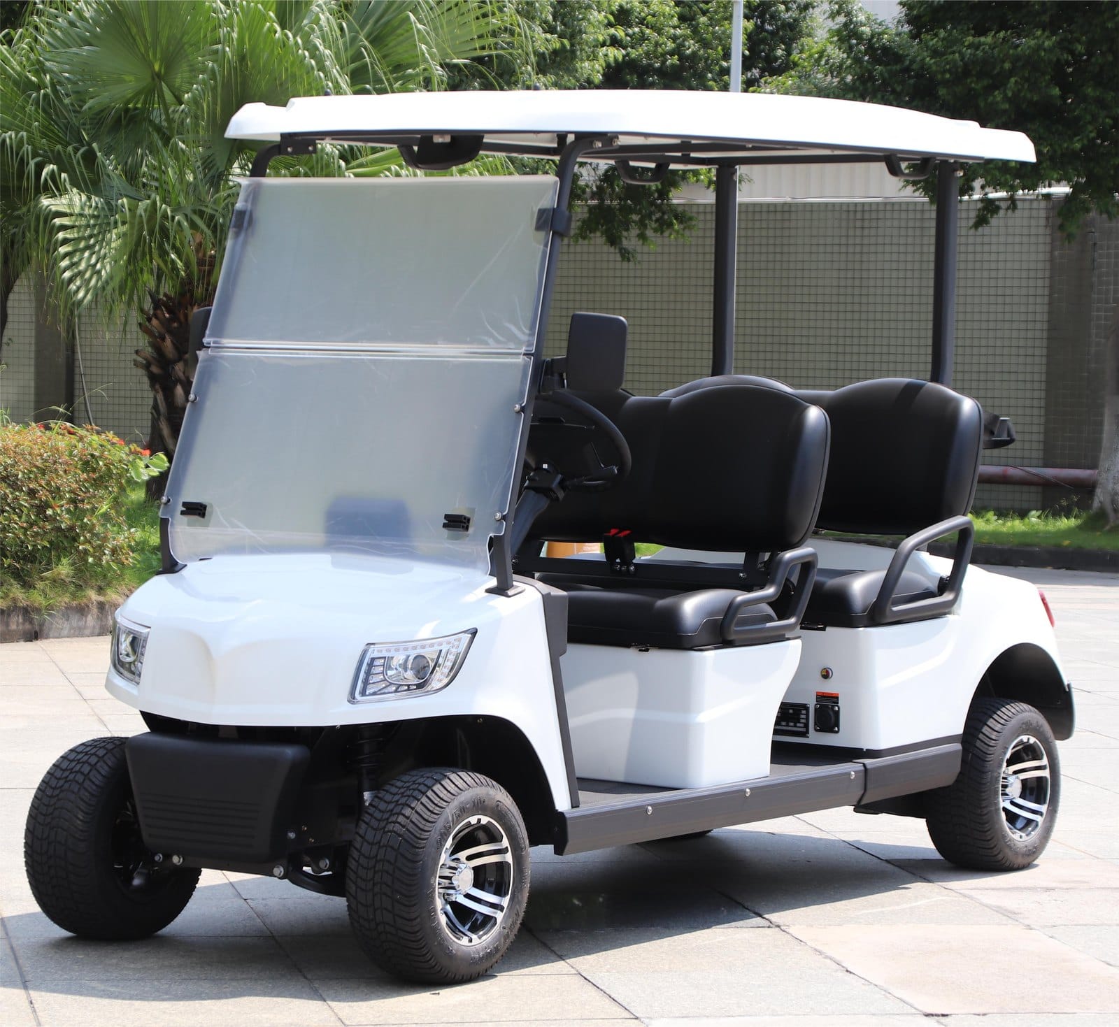 White 4 seater electric golf buggy outdoors, front three quarter view with both benches and alloy wheels